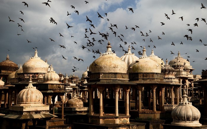 Flock of birds flying over ancient Indian temple domes