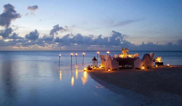 Romantic beach dinner at dusk with torches and lanterns