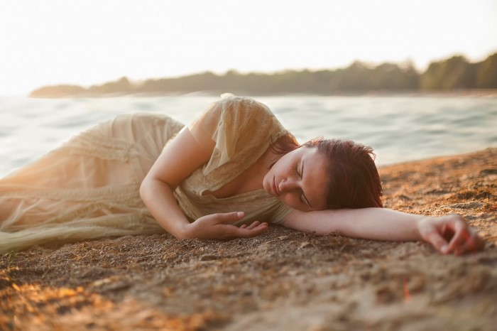 Woman Resting on Sandy Beach at Sunrise