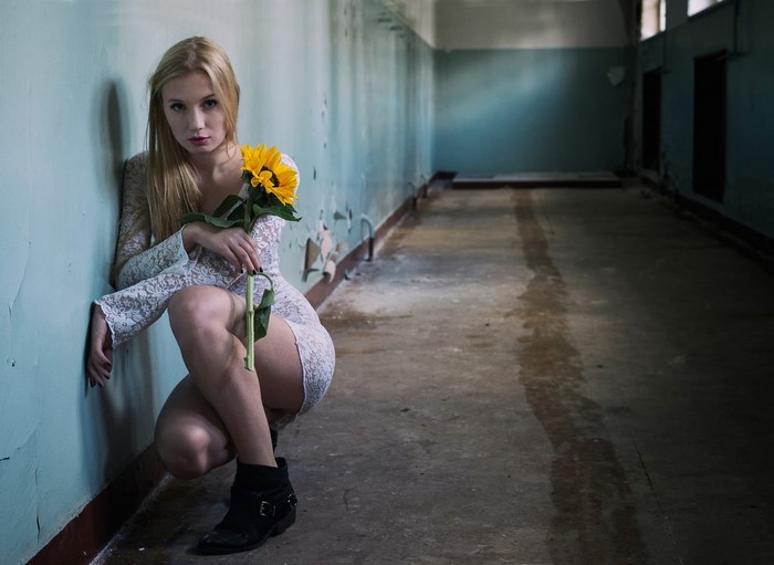 Woman with sunflower in abandoned hallway