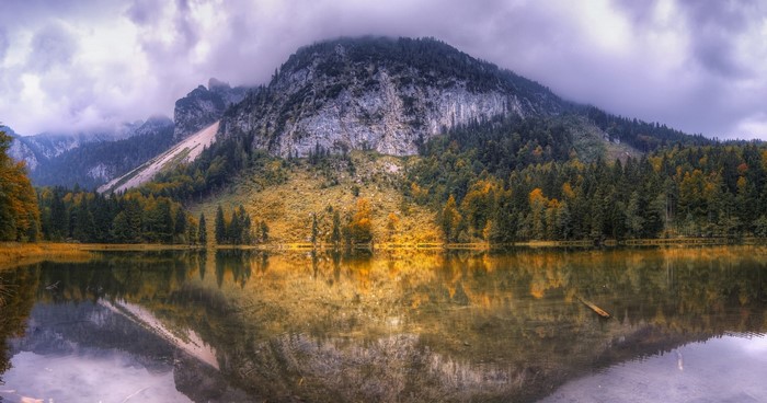 Mountain lake reflection with autumn trees and clouds