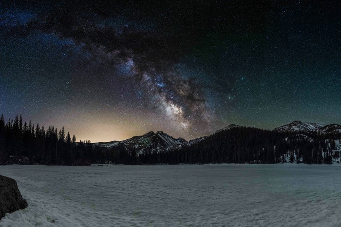 Milky Way over snow-covered mountains and frozen lake