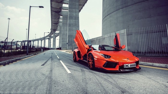 Orange Lamborghini Aventador with Scissor Doors on Road Under Bridge