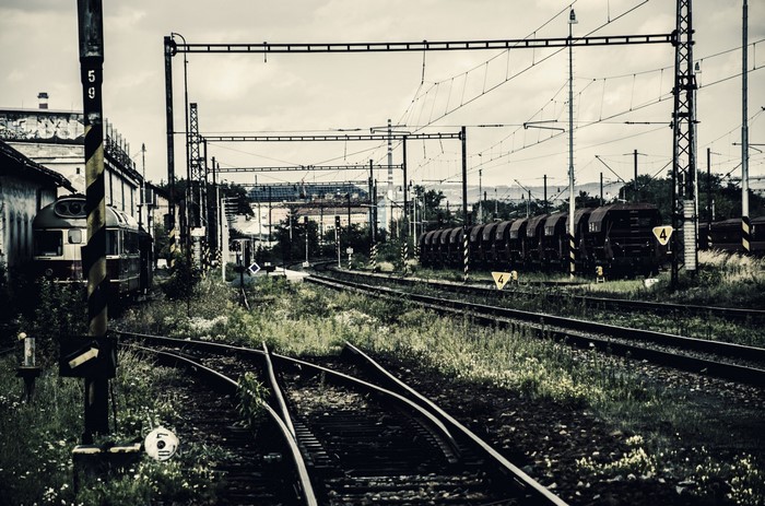 Abandoned train tracks and rusted train cars in a rail yard