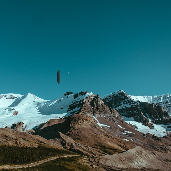 UFO hovering over snow-capped mountains