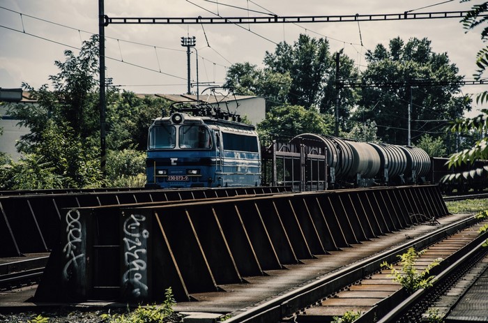 Blue electric locomotive pulling train cars on a railway