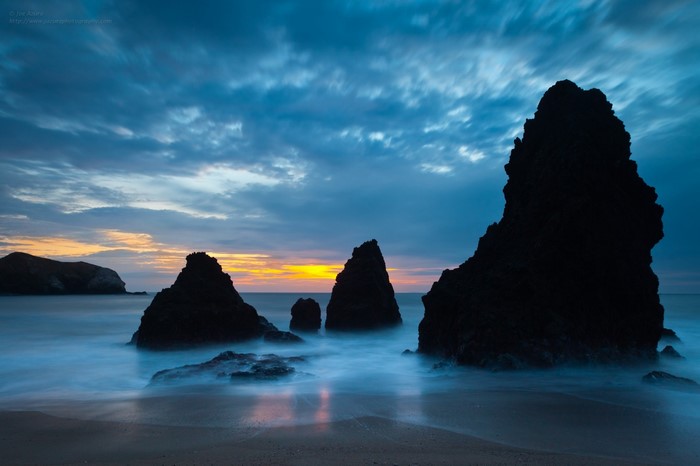 Silhouette rock formations in the ocean at dusk
