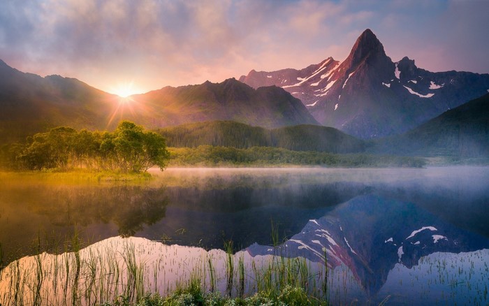 Sunrise over misty lake with mountains and reflection
