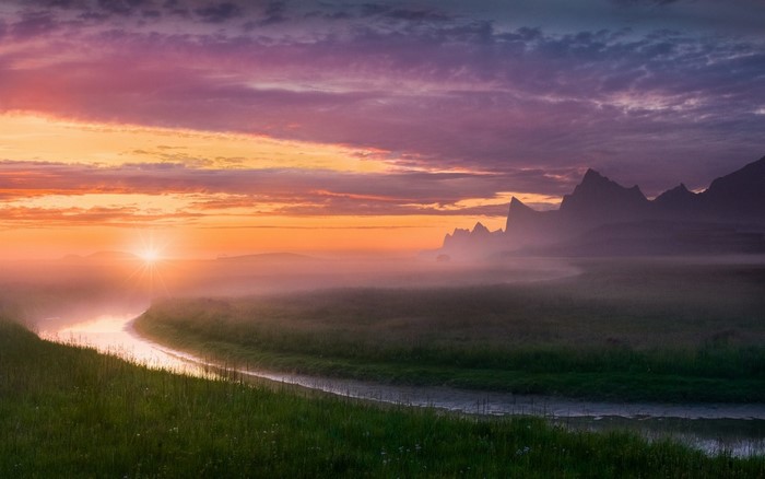 Misty river landscape at sunrise with mountains