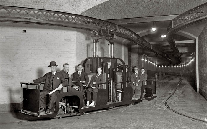 Men in a vintage subway car with overhead track