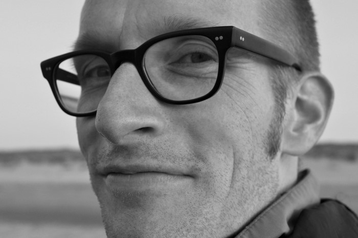 Man wearing black-rimmed glasses in a close-up portrait