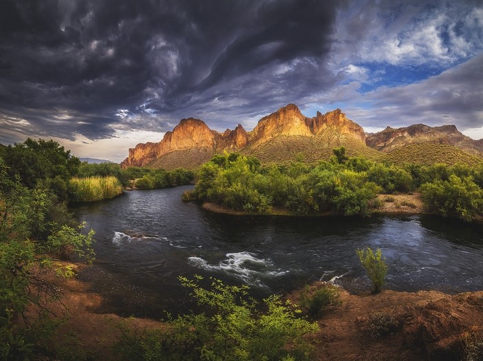 River flowing through mountains under stormy sky