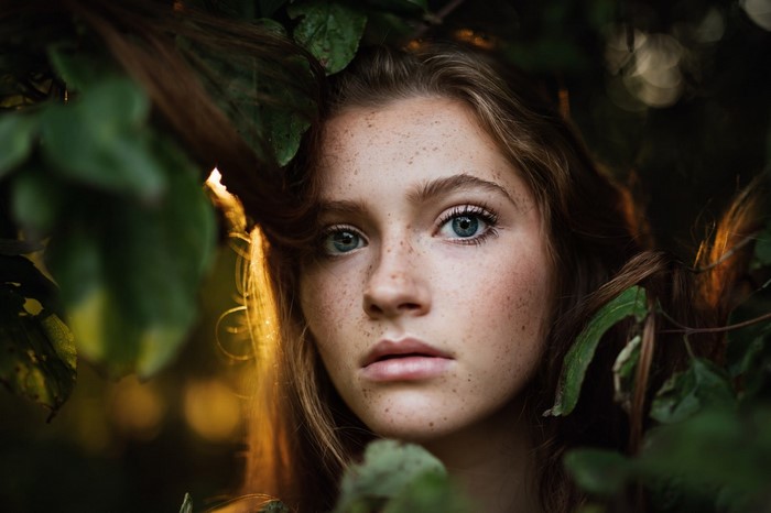 Portrait of a young woman with freckles in nature