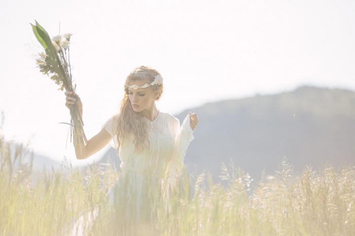 Woman in white dress holding flowers in a field