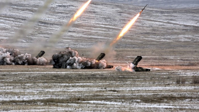 Multiple rockets launching from military vehicles in a field