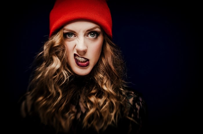 Woman wearing a red beanie and dark clothing