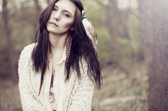 Woman with feathers in hair and cardigan