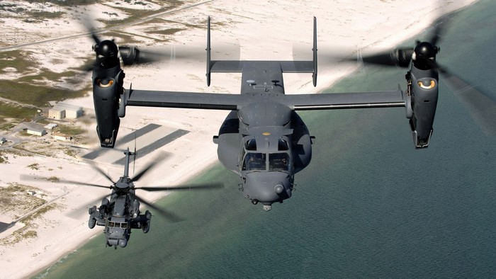 Two military aircraft flying over a coastline