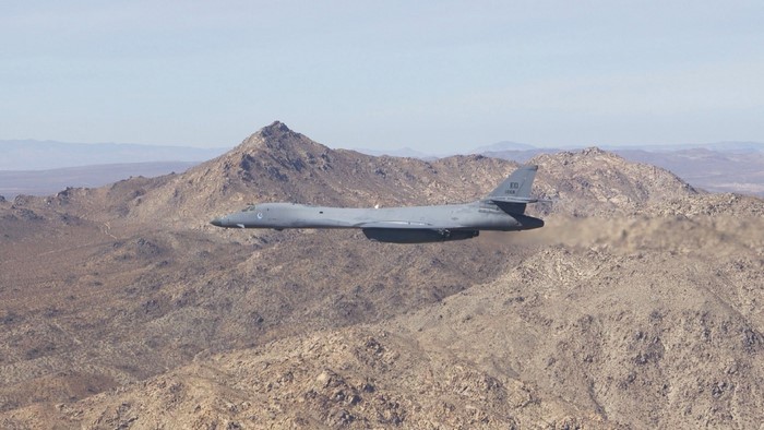 Rockwell B-1 Lancer bomber flying over mountains