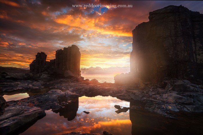 Rocky coast at sunset with reflection in water
