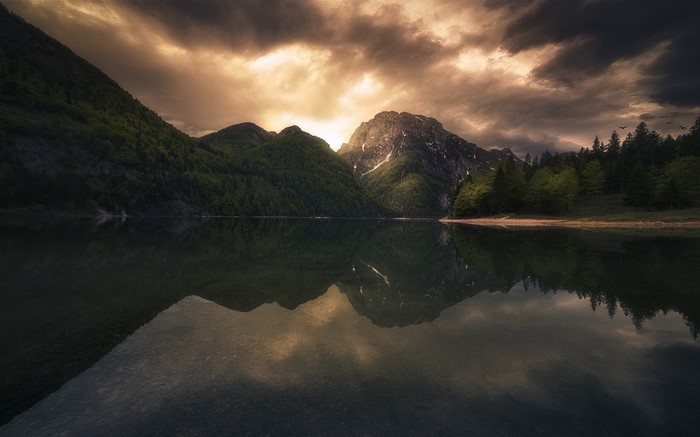 Mountain lake reflection at sunset with dramatic clouds