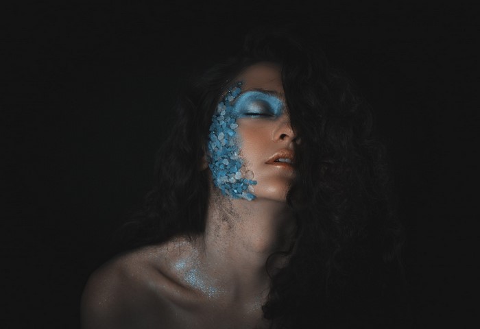 Woman with blue face paint and glitter