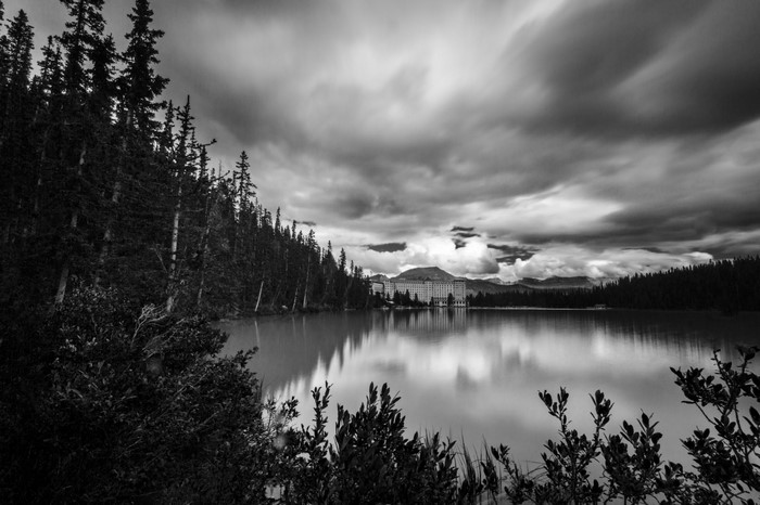 Monochrome landscape of a lake with a building and forest