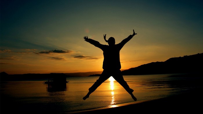 Silhouette of a person jumping at sunset by the sea