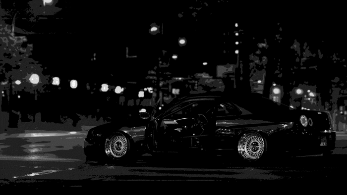 Black sports car parked at night with city lights
