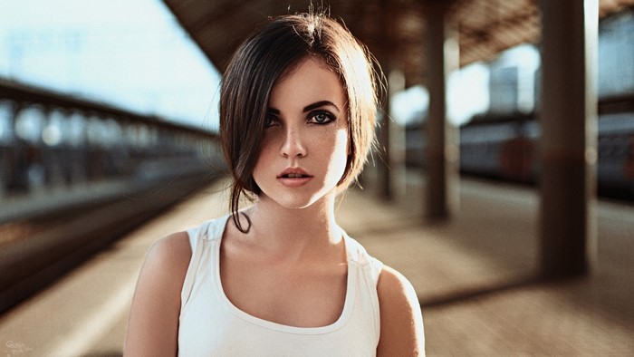 Woman with freckles and smoky eyes at a train station