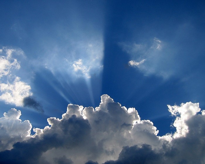 Sunlight beams through clouds in a blue sky