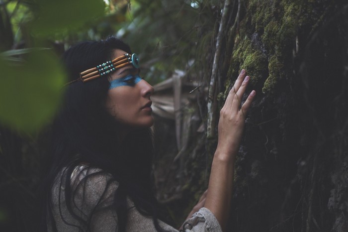 Woman with blue face paint in forest