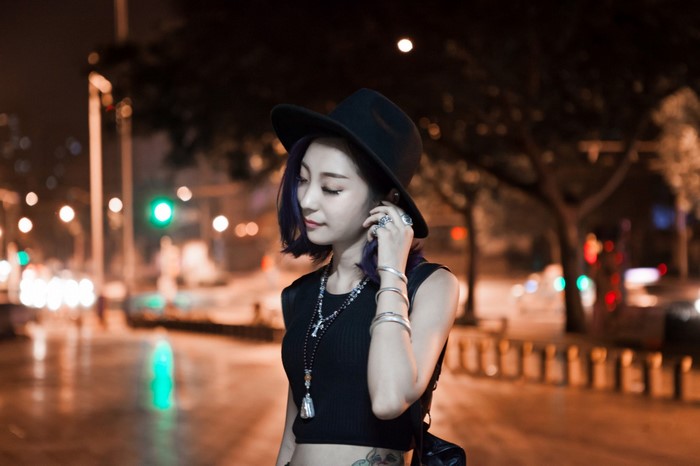 Woman wearing a hat and necklace at night