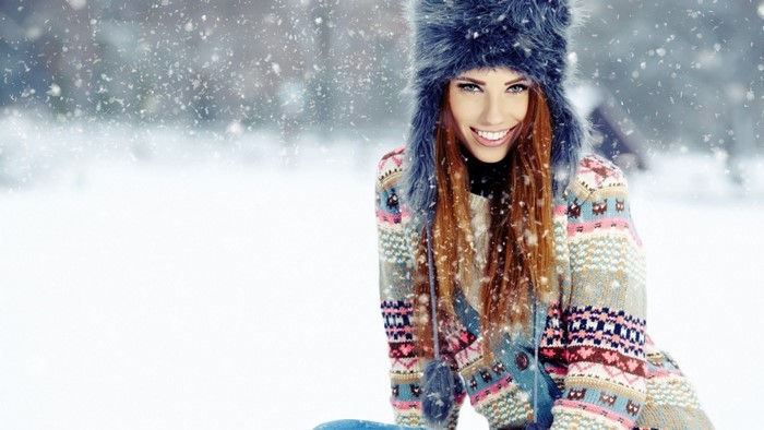 Woman in winter hat and patterned sweater in snow