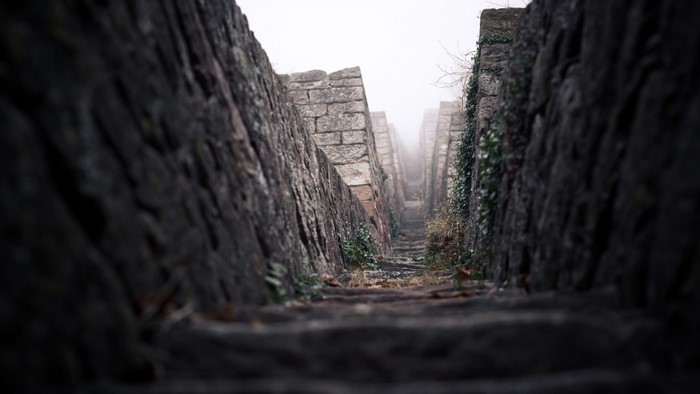 Stone stairs leading up through ancient walls in fog