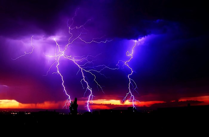 Lightning strikes during a purple and orange sunset storm