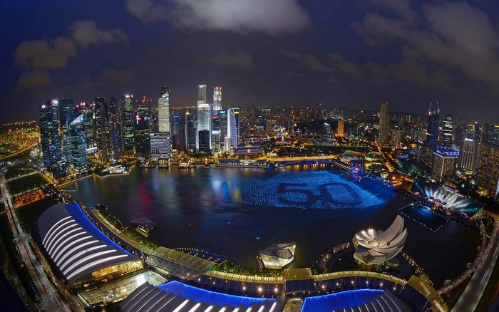Singapore cityscape at night with '50' illuminated on the water