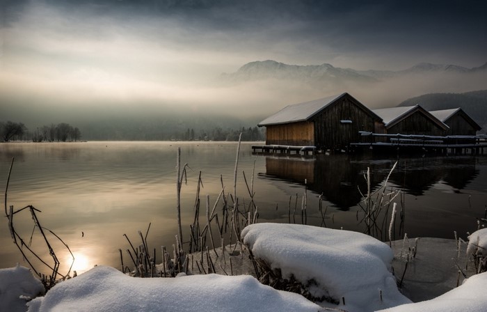 Winter lake with boathouses and misty mountains