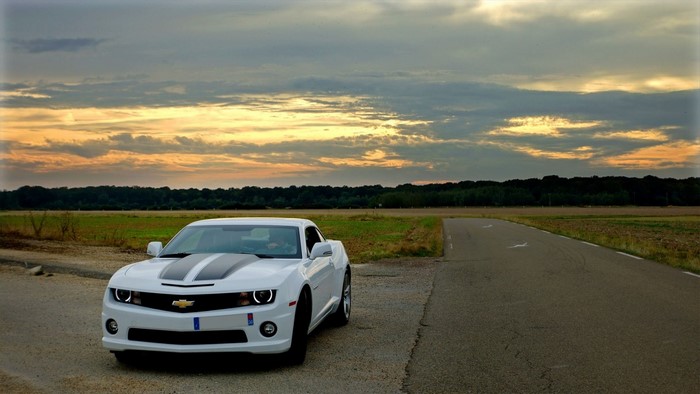 White Chevrolet Camaro on a country road at sunset