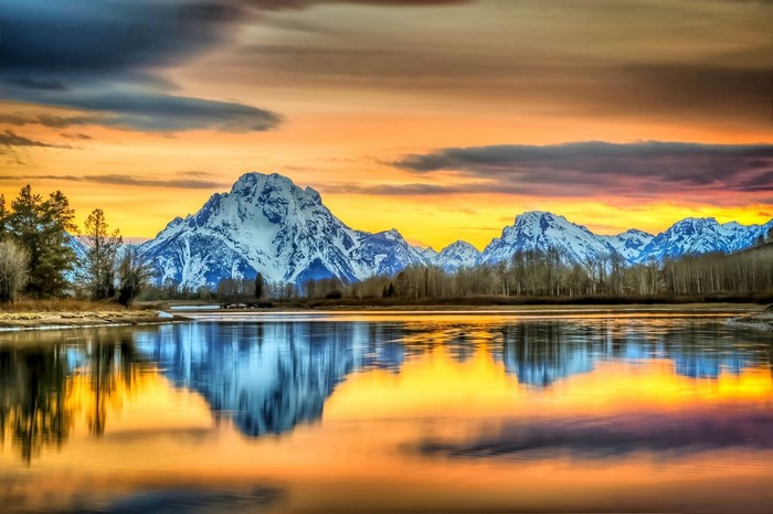 Snowy mountains reflected in a lake at sunset