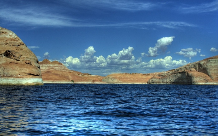 Blue water and sandstone cliffs under a cloudy sky
