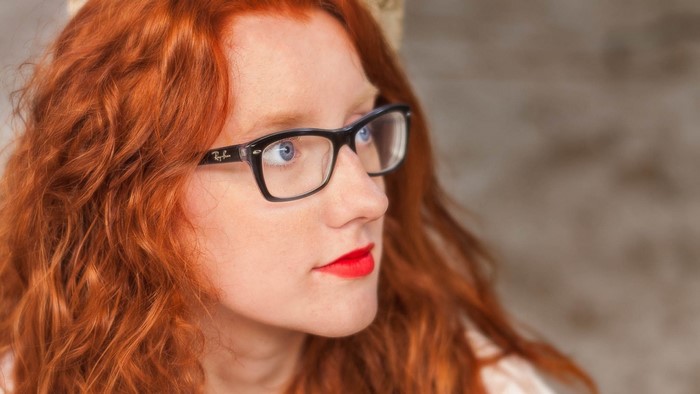 Woman with red hair and glasses wearing red lipstick
