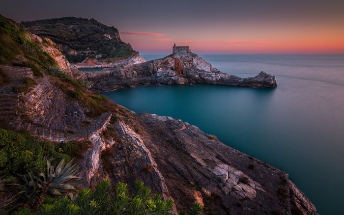 Church on a rocky peninsula at sunset overlooking the sea