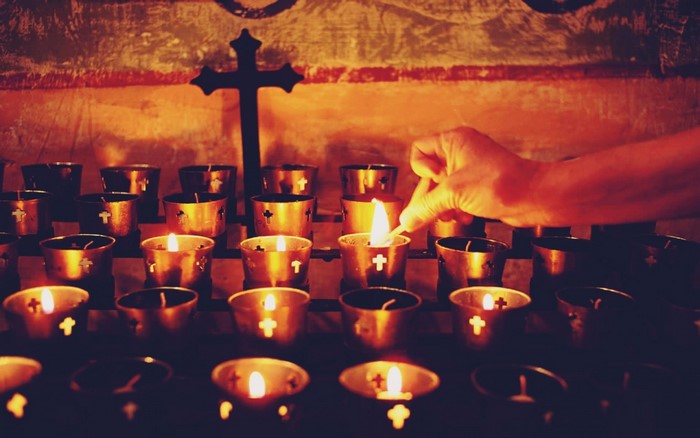 Hand lighting candles in front of a cross