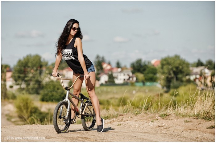 Woman in jean shorts and tank top with BMX bike
