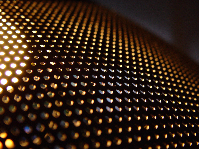 Close-up of a perforated surface with light shining through