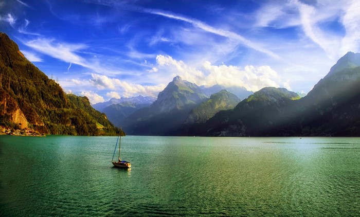 Sailboat on a lake with mountains and clouds