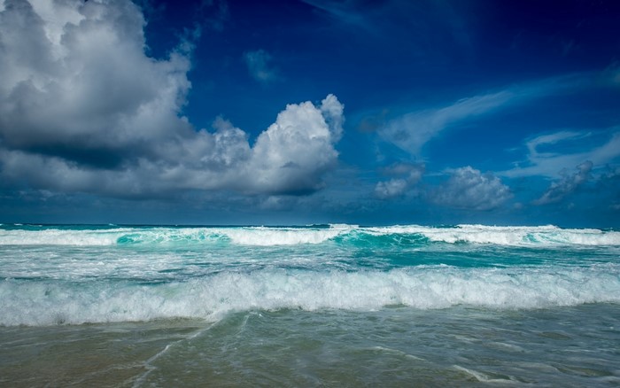 Ocean waves under a cloudy blue sky