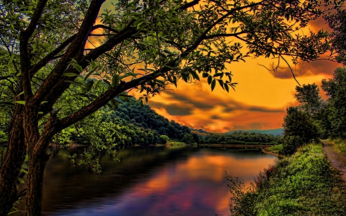 Sunset over a lake with trees and hills