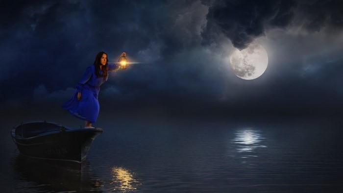Woman in blue dress holding lantern in a boat at night